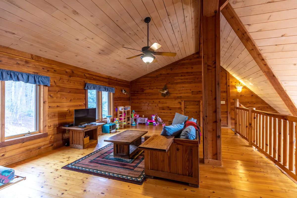 A cozy seating area with wooden walls, colorful children’s toys, and a television. The mood is playful and family-friendly, suggesting opportunities for game nights and movie marathons after a day spent exploring outside.