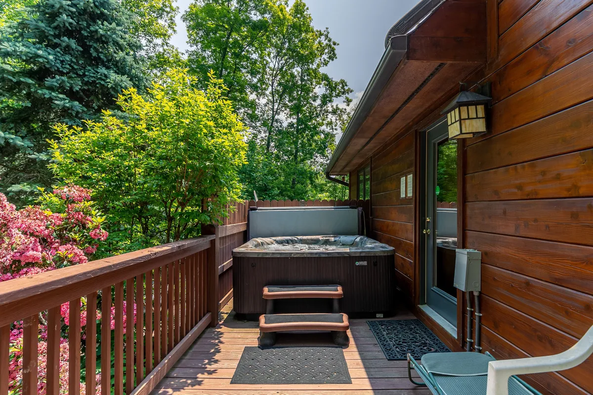 An inviting hot tub on a wooden deck surrounded by greenery, promising relaxation and a touch of luxury. The tranquil environment is ideal for unwinding after a day of mountain adventures, especially under the stars.