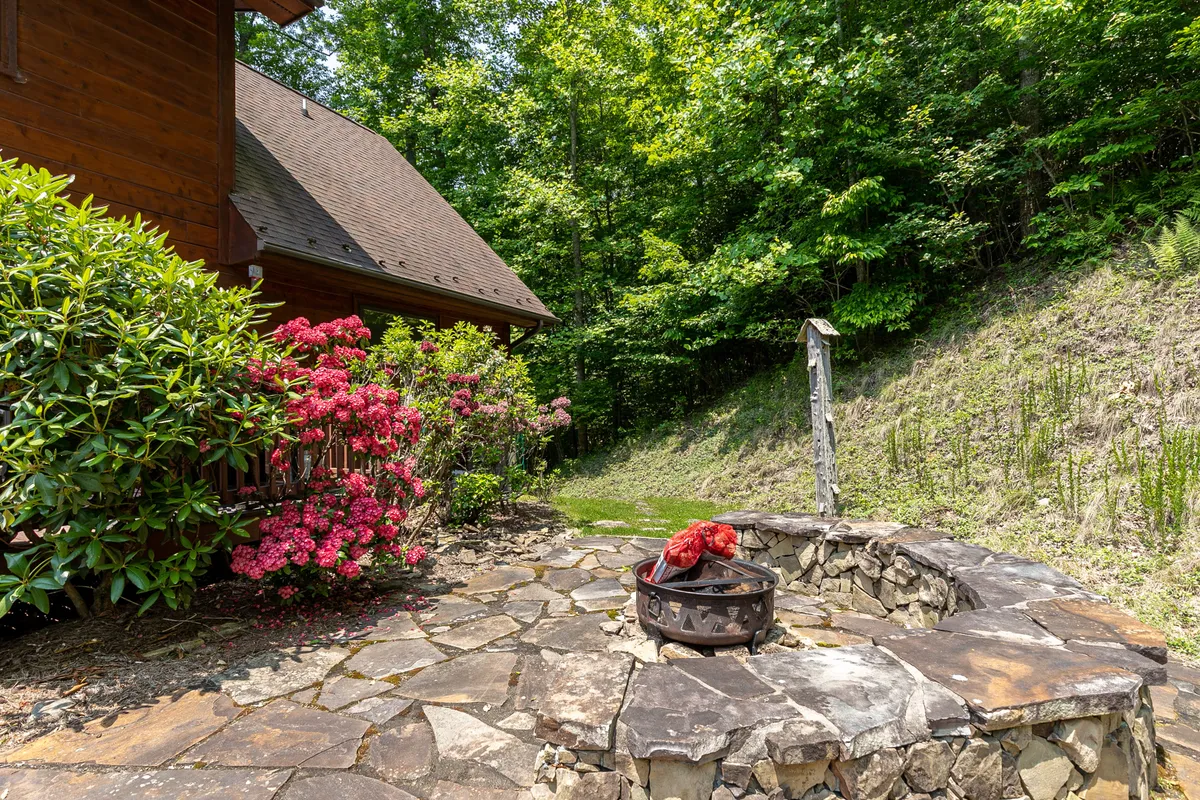 An inviting stone fire pit surrounded by vibrant flowers and lush greenery creates a welcoming outdoor gathering space. The area feels secluded yet open, encouraging moments around the fire after a day of exploration.